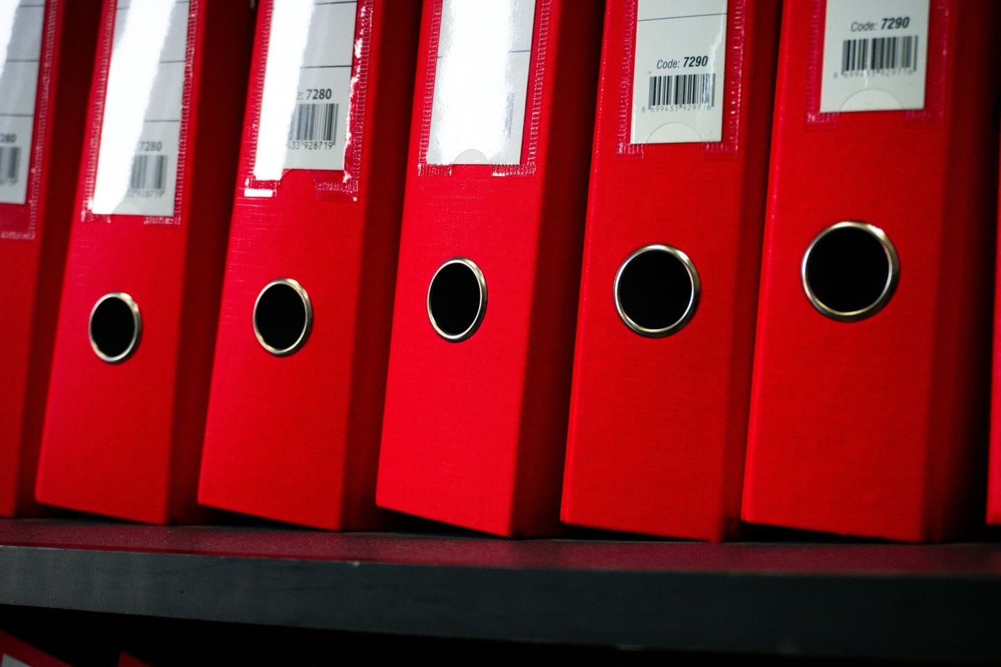 Red file folders stand in a row on a shelf